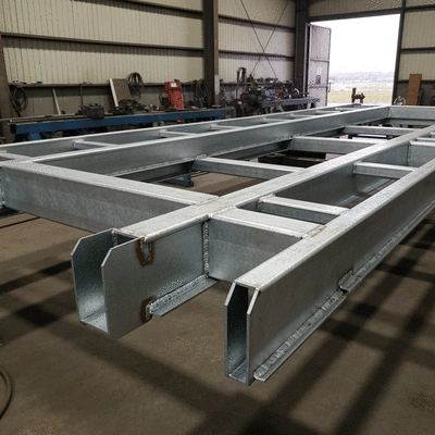 Industrial-grade galvanized steel trailer chassis in a workshop, focusing on reinforced welding and joints